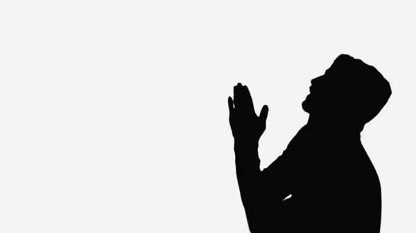 Black shadow of man with praying hands isolated on white — Stock Photo