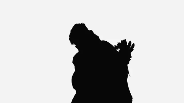 Black silhouette of man embracing woman holding flowers isolated on white - foto de stock