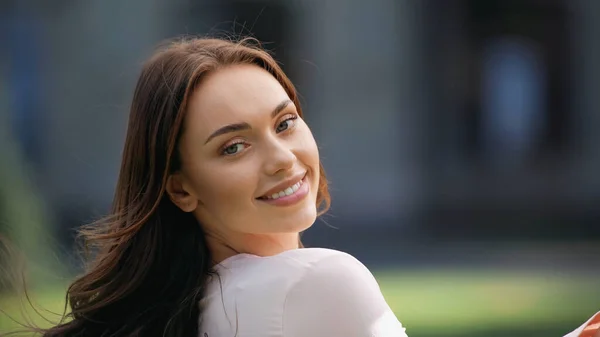 Portrait of smiling brunette woman looking at camera outdoors — Stockfoto