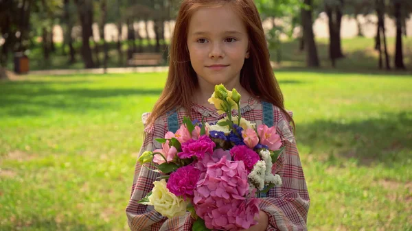Redhead preteen child holding bouquet in park - foto de stock