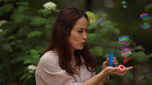 Woman blowing soap bubble in summer park — Stock Photo