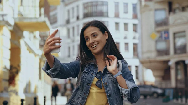 Усміхнена жінка має відеодзвінок на смартфон на міській вулиці — стокове фото
