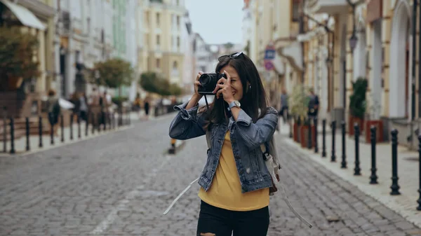 Young traveler taking photo on retro camera on urban street — Stock Photo