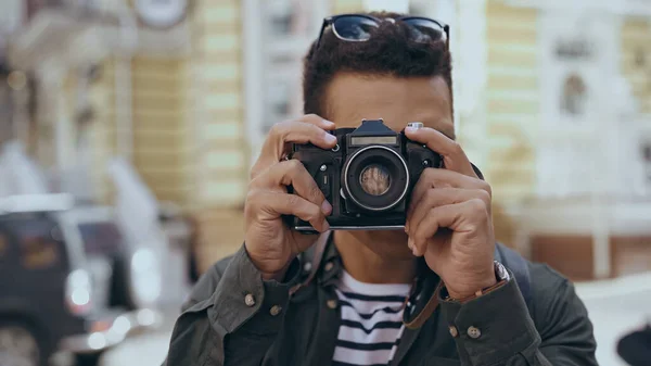 Bi-racial tourist taking photo on film camera outdoors - foto de stock