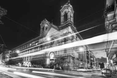 Siyah ve beyaz. Havalı uzun markalı arabalar. Trafikte neon ışıkları, Roma caddesinde gece görüşü, İtalya. Chiesa di Santa Maria Immacolata all 'Esquilino' nun önünde