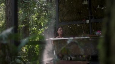 Yağmur sırasında bir ormanda küvette bir kız. Lüks bir kaplıcada tropikal yağmur ormanlarında banyoda dinlenen genç ve güzel bir kadın.