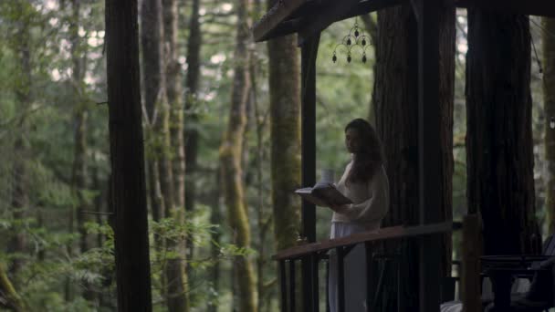 Young Woman Reading Book Drinking Hot Tea Porch Cozy Cabin — Vídeos de Stock