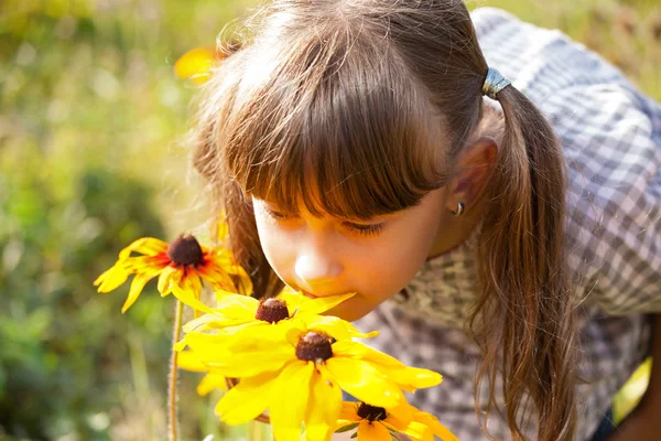 Menina cheirando uma flores amarelas — Fotografia de Stock