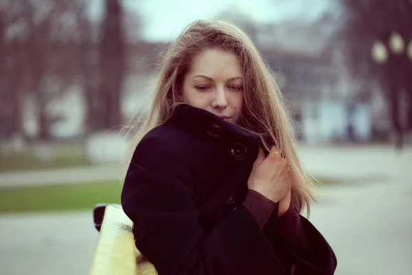 Young woman wrapped in a coat from the cold — Stock Photo, Image