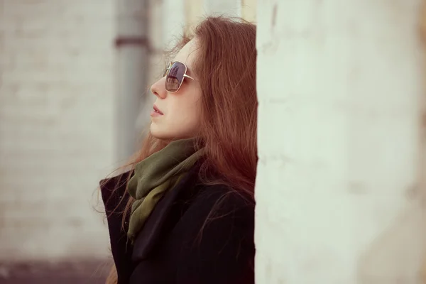 Mladá žena s brýlemi proti zdi doma — Stock fotografie