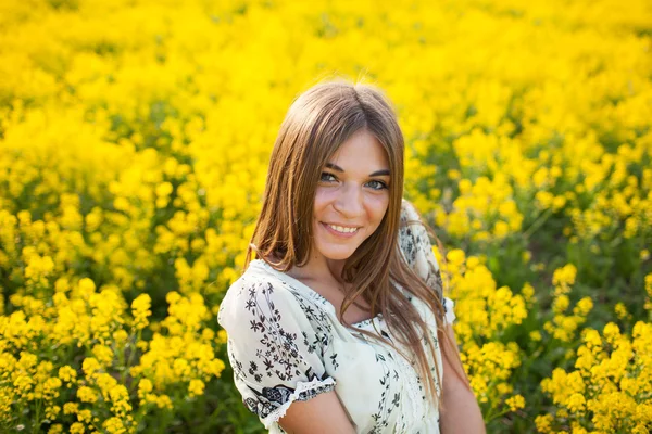 Mulher bonita entre flores amarelas em um campo — Fotografia de Stock