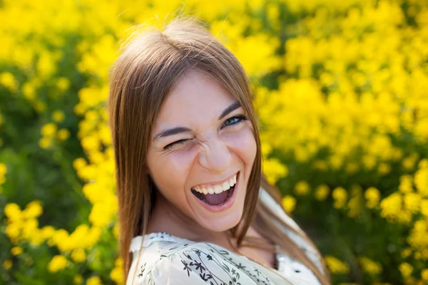 Playful young woman among yellow flowers — Stock Photo, Image