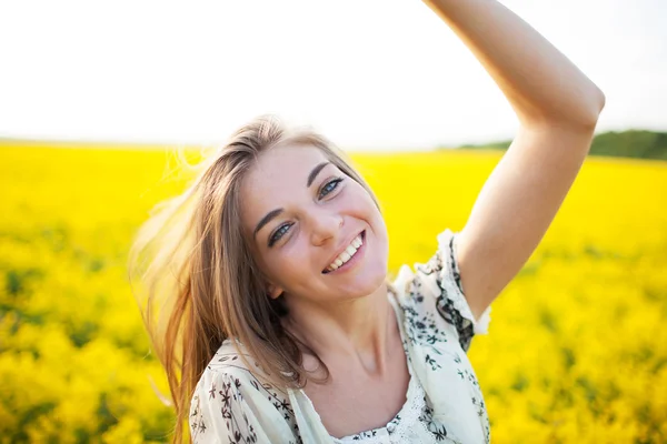 Mooie vrouw onder gele bloemen in een veld — Stockfoto