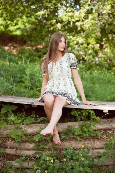 Hermosa chica se sienta en las tablas — Foto de Stock