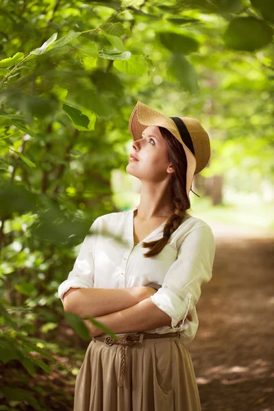 Mulher bonita em um chapéu entre folhagem verde — Fotografia de Stock