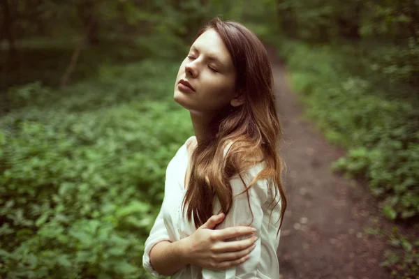 Unhappy girl standing in the middle of a forest — Stock Photo, Image