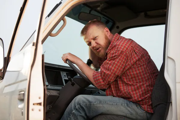 Somewhat puzzled bearded driver in the cab — Stock Photo, Image