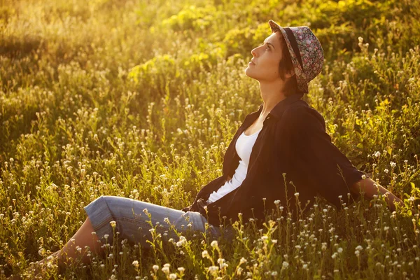 Menina senta-se entre as flores selvagens — Fotografia de Stock