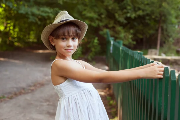 Girl in the hat next to a fence — Stock Photo, Image