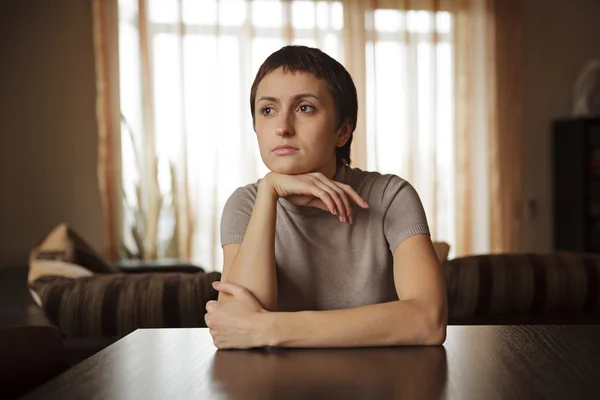 Beautiful young woman sitting at the table — Stock Photo, Image