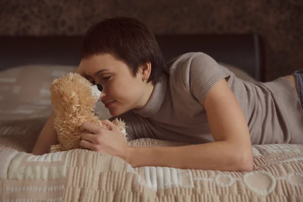 Girl lying on the bed with a teddy bear — Stock Photo, Image