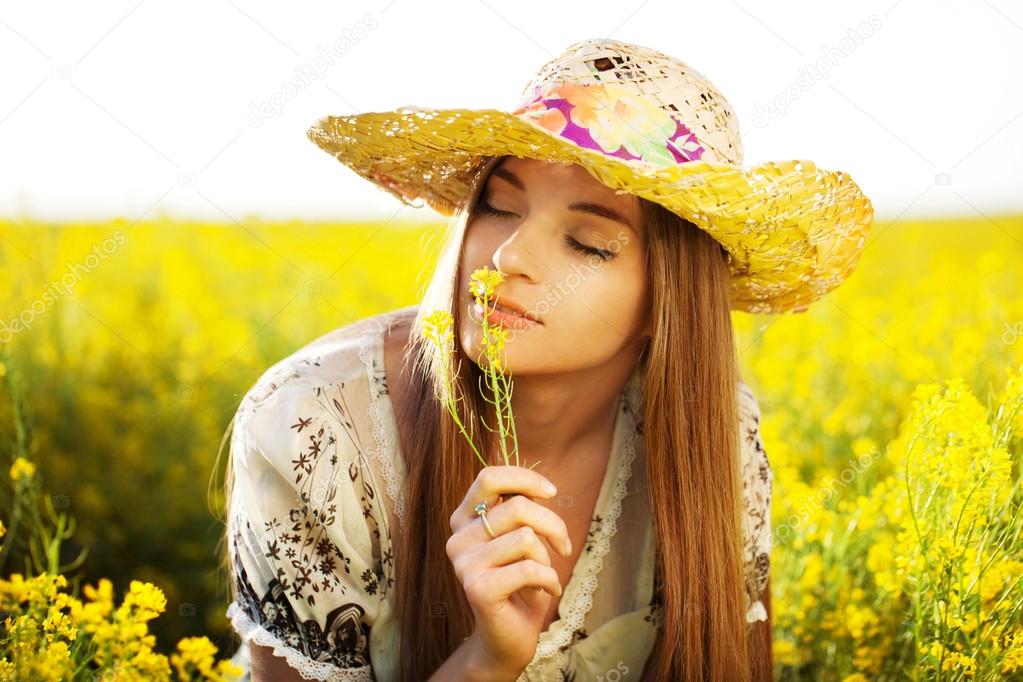 Happy girl enjoys the smell of a flower