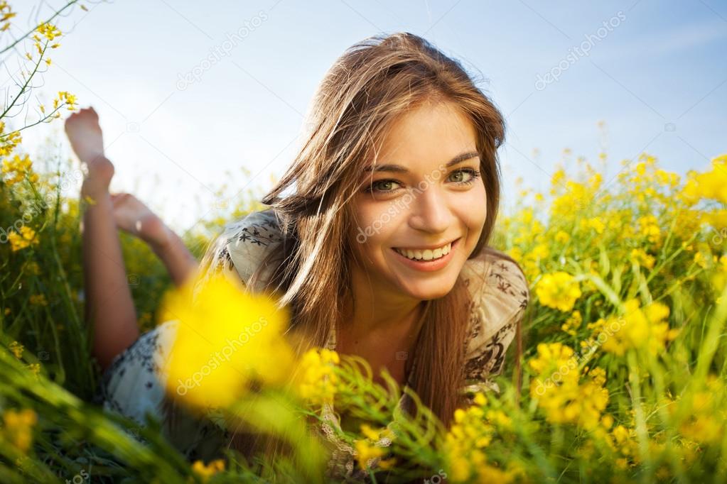 Happy girl lies among yellow wildflowers