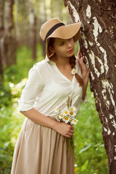 Schöne Frau mit einem Strauß Gänseblümchen in Birkennähe — Stockfoto