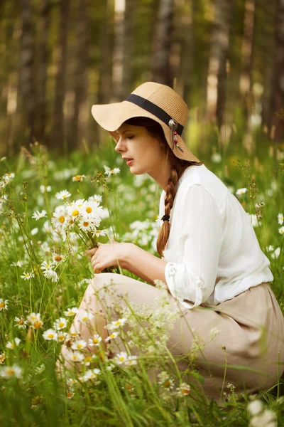 Mulher bonito arranca margaridas em um prado — Fotografia de Stock