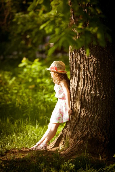 Chica de pie cerca de un árbol en la luz del sol —  Fotos de Stock