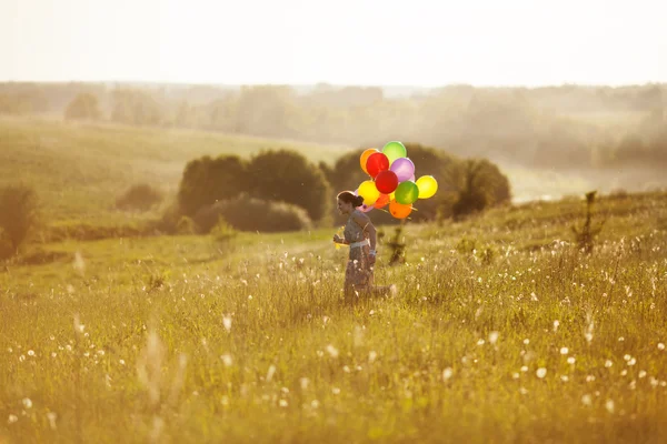 Glad tjej med ballonger som körs på fältet — Stockfoto