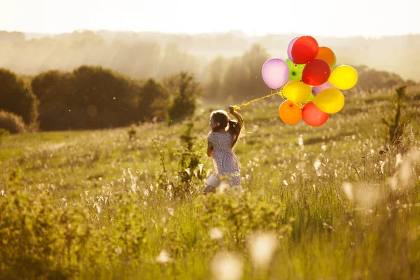 Meisje loopt over het veld met opblaasbare ballen — Stok fotoğraf