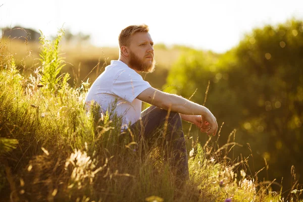 Mann sitzt abends auf dem Gras — Stockfoto