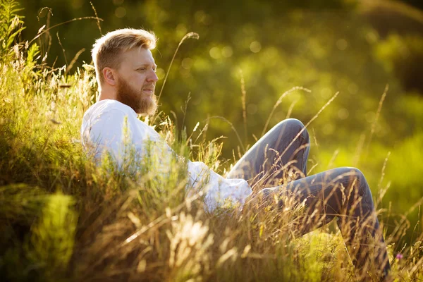 Hombre feliz en la hierba y mira a la distancia —  Fotos de Stock