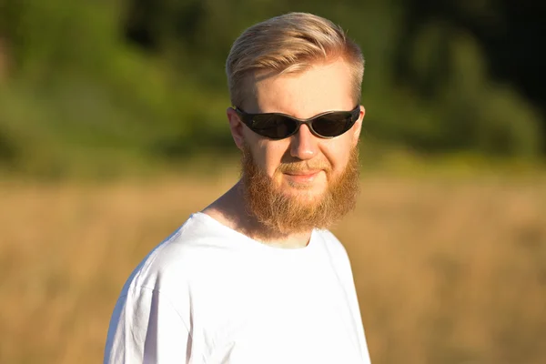 Jonge glimlachend bebaarde man in zonnebril — Stockfoto