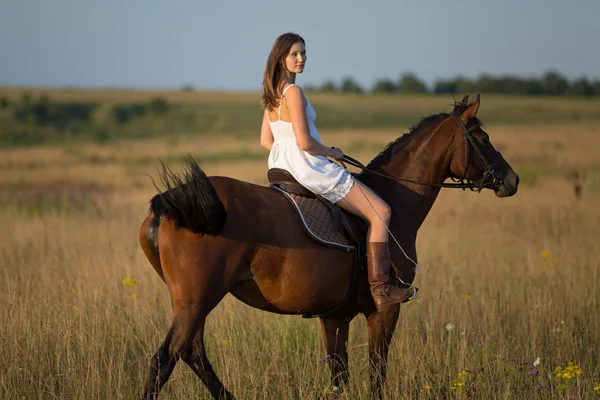 Chica en vestido blanco cabalgando en un caballo — Foto de Stock