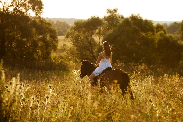 Ung kvinna på en brun häst — Stockfoto