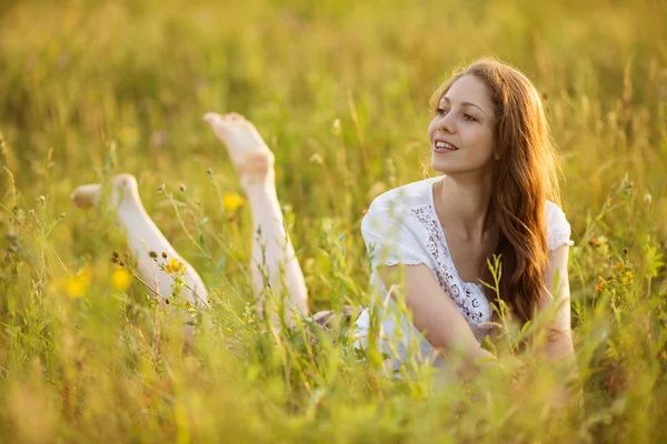 Jeune femme heureuse regarde hors de l'herbe — Photo