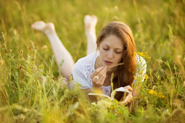 Meisje met een boek van wilde bloemen — Stockfoto