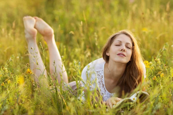 Glad tjej med en bok i gräs drömmer — Stockfoto