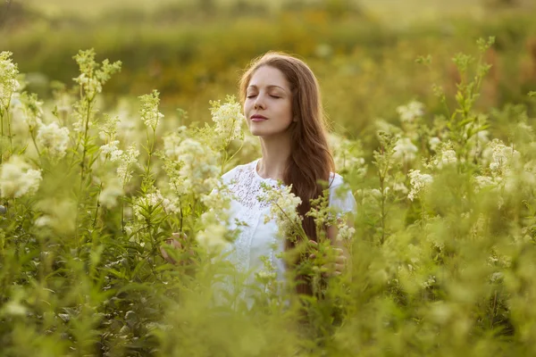 Glad kvinna med ögonen stängda bland de vilda blommor — Stockfoto