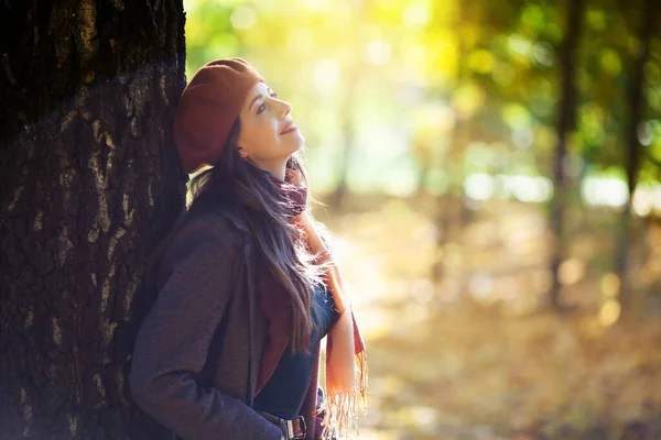 秋の晴れた日にはオレンジのベレー帽の女の子が木の横に立っています — ストック写真