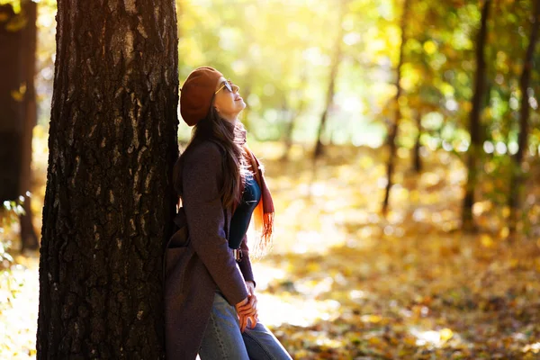 ベレー帽の女の子は晴れた秋の日に木にもたれて立っている — ストック写真