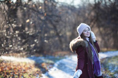 Genç ve güzel bir kadın sonbahar parkında yürüyor.