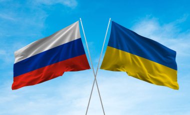 Mavi gökyüzünde dalgalanan Ukrayna ve Rus bayrakları.