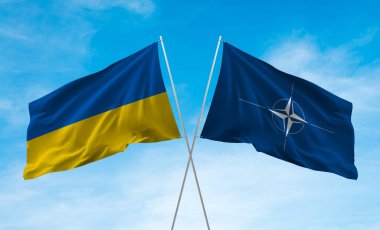 Mavi gökyüzünde sallanan Ukrayna ve NATO bayrakları.