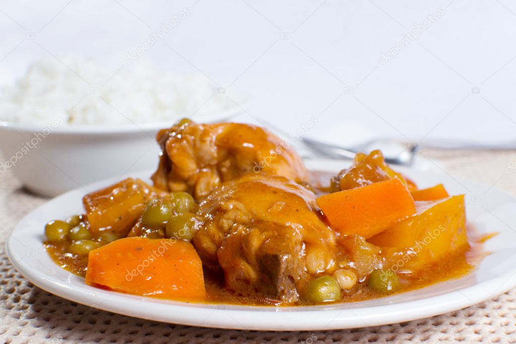 chicken afritada with bowl of rice closeup