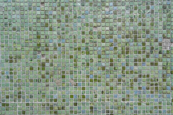 Green and turquoise ceramic glossy tiles on the wall, textured.
