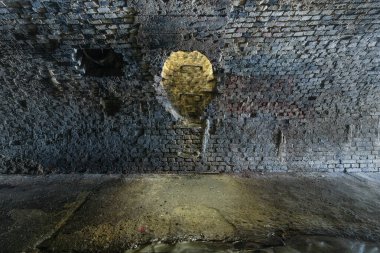 Descent with a ladder into a brick underground rainwater collector.