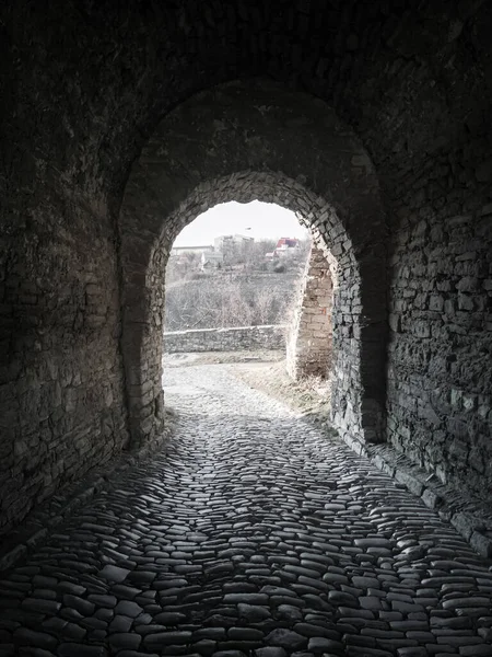 Exit from the old dark brick arched tunnel of the 18th century fortification. Light in the end of old abandoned tunnel.